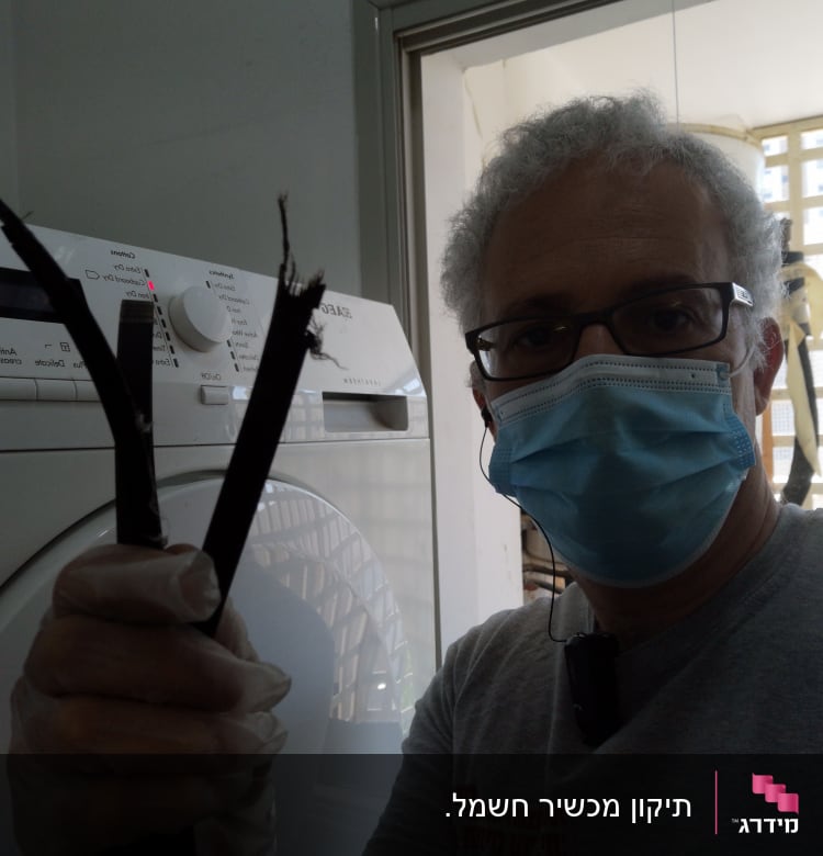 אדם מחזיק כבלים חתוכים ליד מכונת כביסה